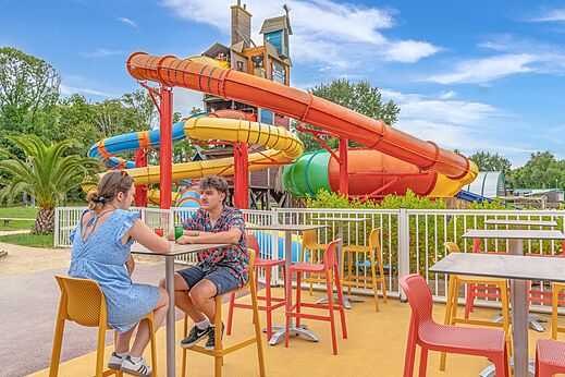 Kleurrijke waterglijbanen en buitenterras van de bar op camping CAPFUN Lodge in SARZEAU (56).