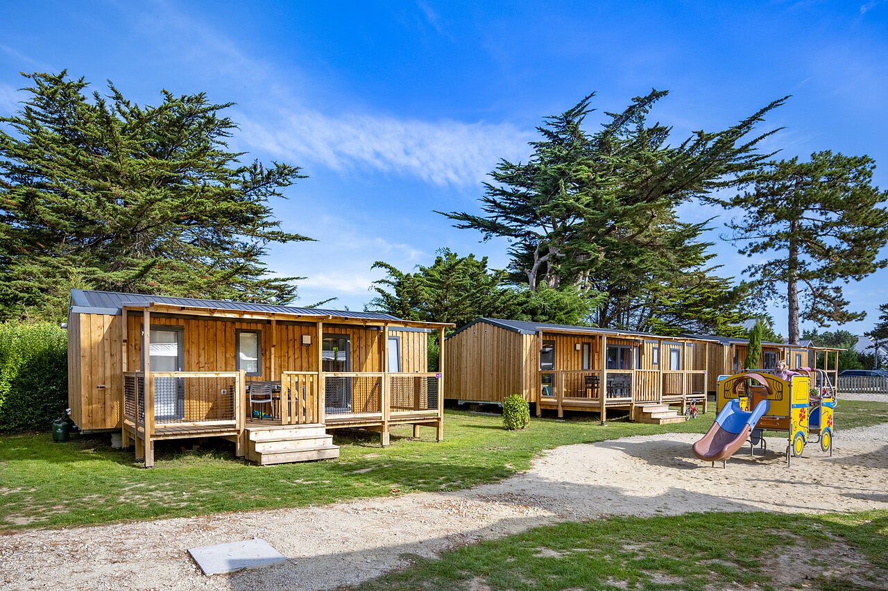 Houten stacaravans, terrassen en kinderspeeltuin op camping CLICOCHIC Longchamp.