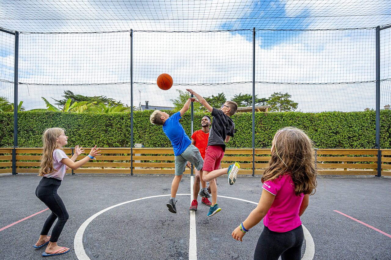 Kinderen basketballen op multisportterrein op camping CLICOCHIC Longchamp in Saint Lunaire (35).