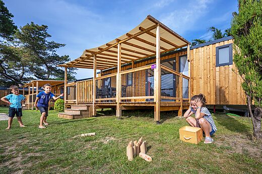 Houten stacaravans en spelende kinderen op camping CLICOCHIC Longchamp in Saint Lunaire (35).