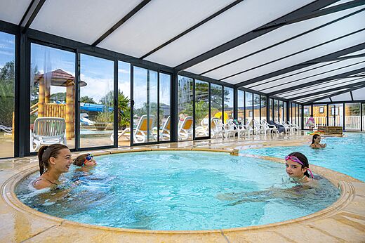 Overdekt zwembad met jacuzzi, kinderen, glijbaan op camping CLICOCHIC Longchamp in Saint Lunaire.