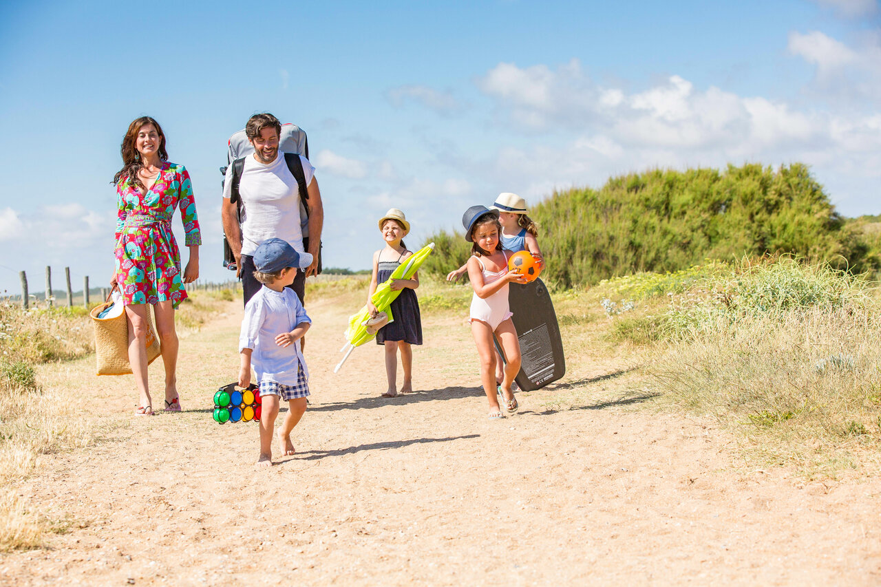 Familie wandelt op zandpad met strandspullen op camping CAPFUN Loubine in Les Sables d'Olonne (85).