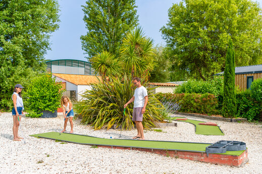 Minigolf met familie spelend op groene baan op camping CAPFUN Loubine in Les Sables d'Olonne (85).