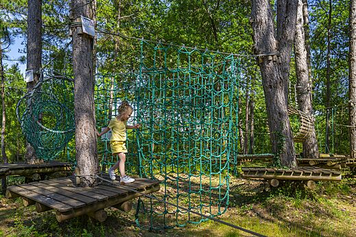 Kind op een avonturenparcours in de bomen op camping CLICOCHIC Lou Castel in Castelnaud-la-Chapelle (24).