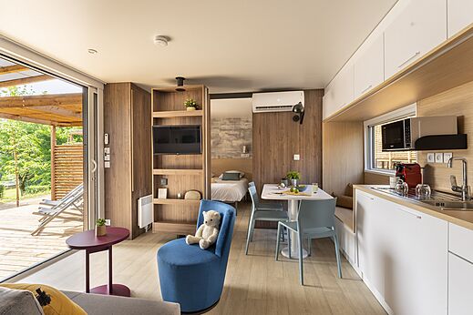 Modern Mobil-home interieur met woonkamer, keuken en terras op camping CLICOCHIC Lou Castel.