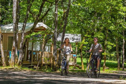 Stel fietst op bospad langs Mobil-homes op camping CLICOCHIC Lou Castel.