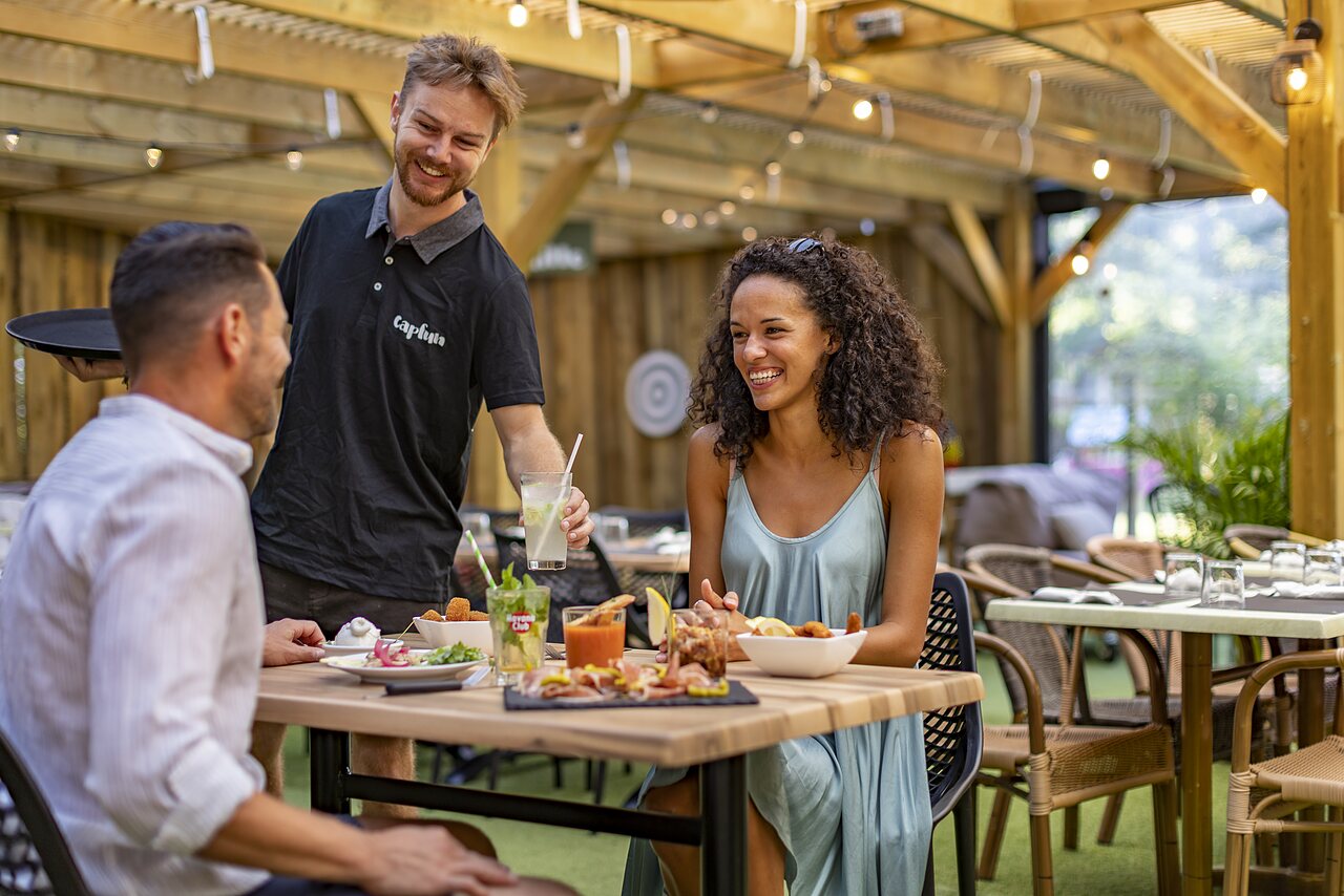 Koppel dineert op terras, lachende ober bij CAPFUN Lou Puntaou in LEON.