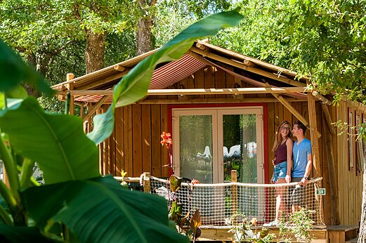 Houten Mobil-home met terras en lachend stel op camping CAPFUN Lou Puntaou in LEON (40).