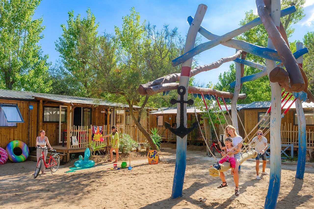 Speeltuin met schommel en stacaravans op camping CAPFUN Lou Village in Vendres (34).