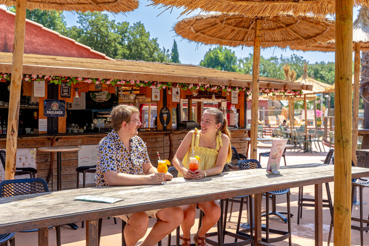 Paar met cocktails aan de buitenbar, camping CAPFUN Mael in ARGELES SUR MER (66).