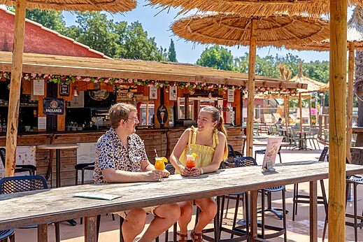 Lachend stel met cocktails bij de bar-restaurant van camping CAPFUN Mael in ARGELES SUR MER (66).