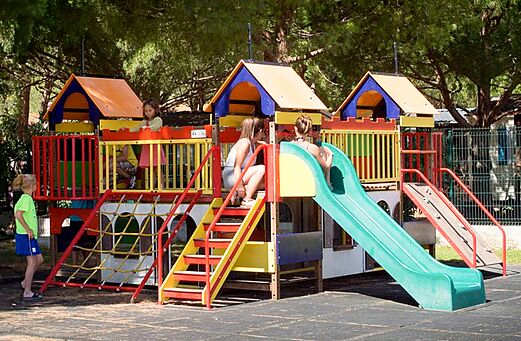 Kleurrijke speeltuin met glijbanen en kinderen op camping VAGUES OCEANES Manoir de Balkos in Valras-Plage (34).