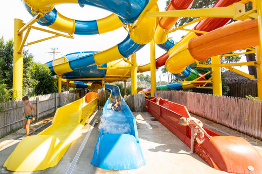 Kleurrijke waterglijbanen met spelende kinderen op camping CAPFUN Marina d'Aléria in Aleria (20).