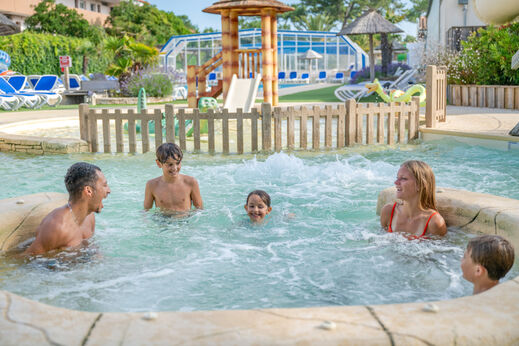 Vrolijke familie in de jacuzzi van het zwembad op camping VAGUES OCEANES Marina Landes.