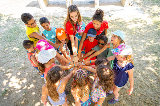 Kinderen en animatoren in een cirkel, handen samen voor groepsactiviteit op camping VAGUES OCEANES Marina Landes in Mimizan (40).