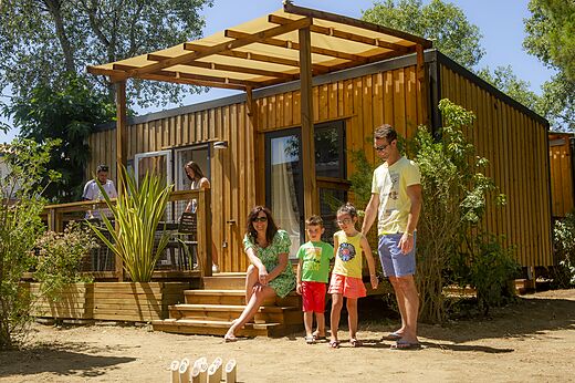 Familie speelt voor een modern stacaravan met terras op camping VAGUES OCEANES Marinette in Ste Marie La Mer (66).