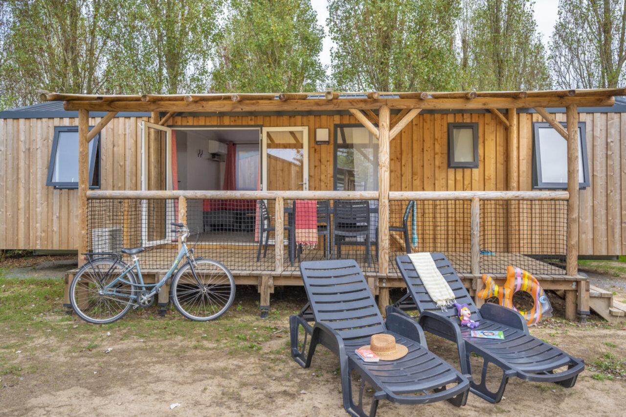 Houten stacaravan, ingericht terras, ligstoelen, fiets op camping CLICOCHIC M�doc Bleu.