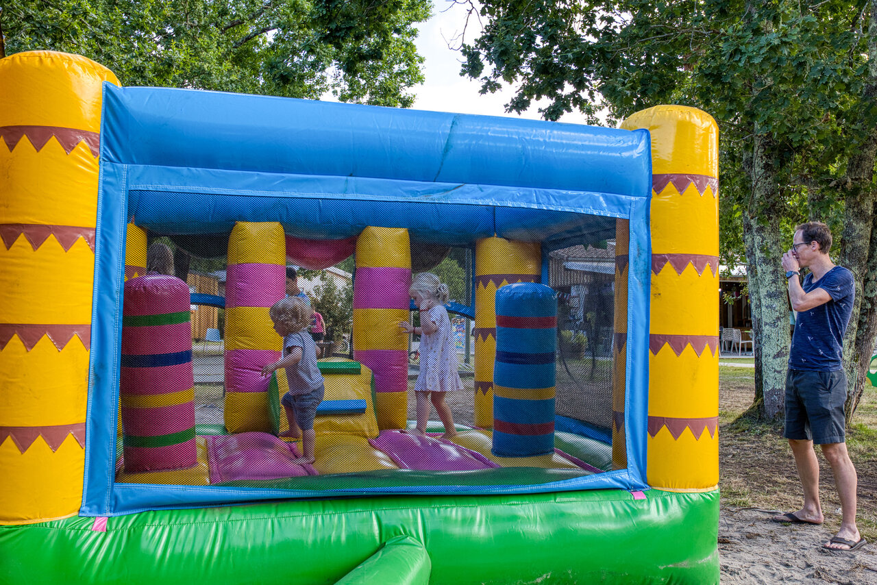 Kleurrijk springkasteel met spelende kinderen op camping CLICOCHIC M�doc Bleu in Carcans (33).