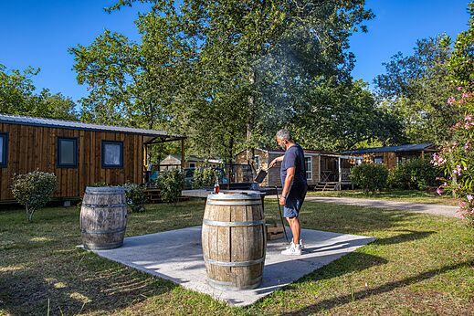Man barbecuet voor Mobil-homes op camping CLICOCHIC Médoc Bleu in Carcans (33).