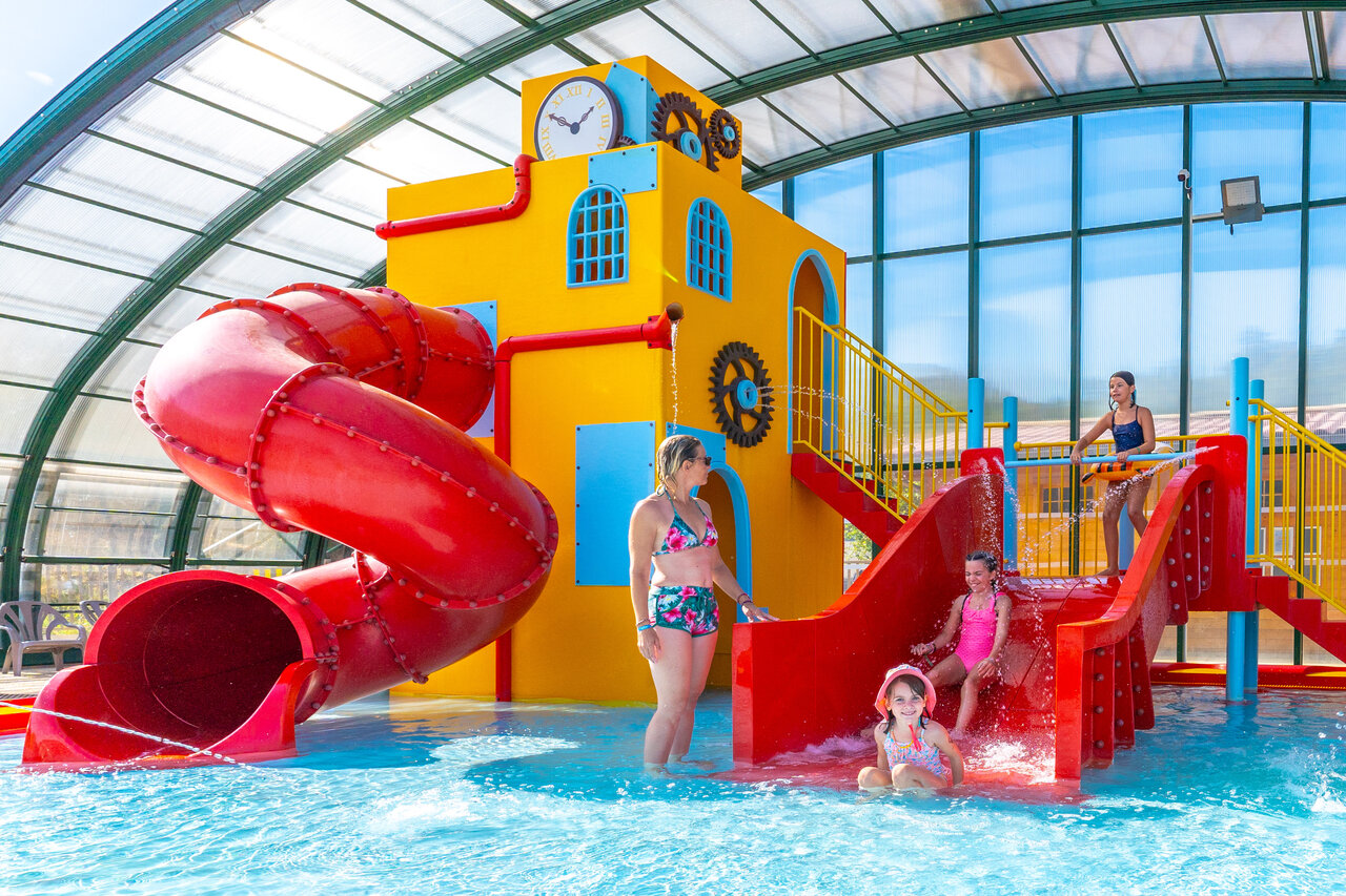Overdekt zwembad met glijbanen en waterspellen op camping CAPFUN Merle Roux.
