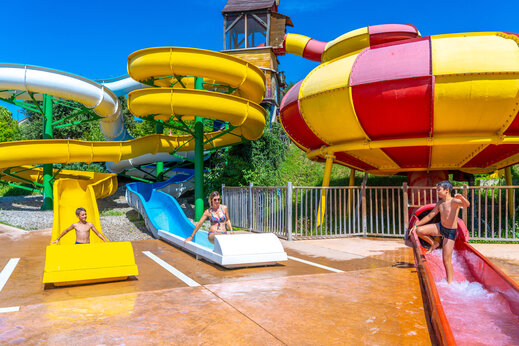 Grote, kleurrijke waterglijbanen met kinderen op camping CAPFUN Merle Roux (07).