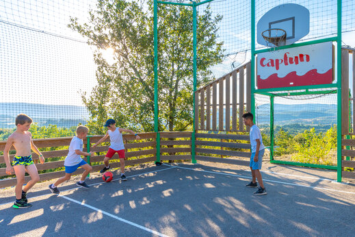Kinderen voetballen op multisportterrein camping CAPFUN Merle Roux in Baix (07).