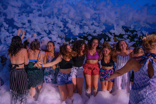 Lachende groep jongeren geniet van een geanimeerd schuimfeest op camping CAPFUN Merle Roux in Baix (07).