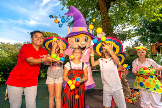 Animatieteam, kinderen en Capfun mascotte spelen met ballen op camping CAPFUN Merle Roux in Baix (07).