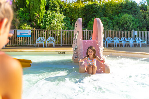 Meisje op waterglijbaan in ondiep zwembad op camping CAPFUN Merle Roux in Baix (07).