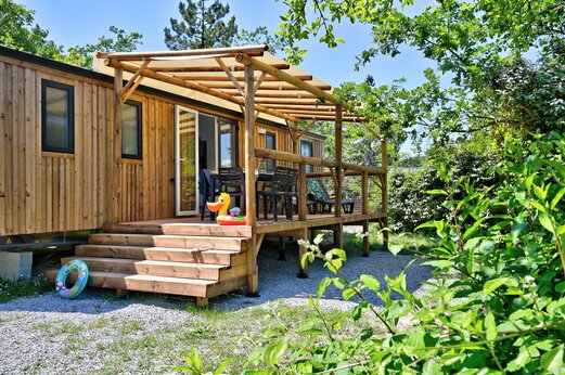 Houten stacaravan met overdekt terras en buitenmeubilair op camping CAPFUN Merle Roux in Baix (07).