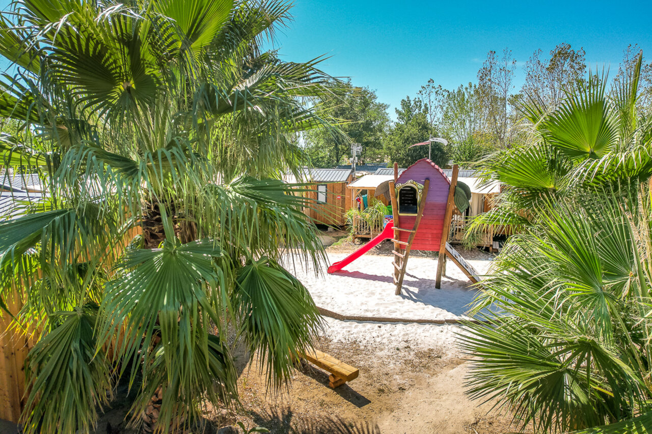 Kinderspeeltuin met rood speelhuisje en glijbaan op camping CAPFUN Mer et Soleil in Cap d'Agde (34).