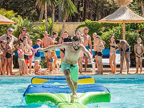 Man op opblaasbaar waterparcours in zwembad camping CAPFUN Mer et Soleil.