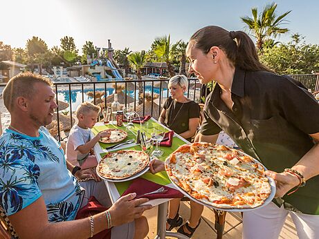 Familie eet pizza's in restaurant, uitzicht zwembad, camping CAPFUN Mer et Soleil in Cap d'Agde (34).