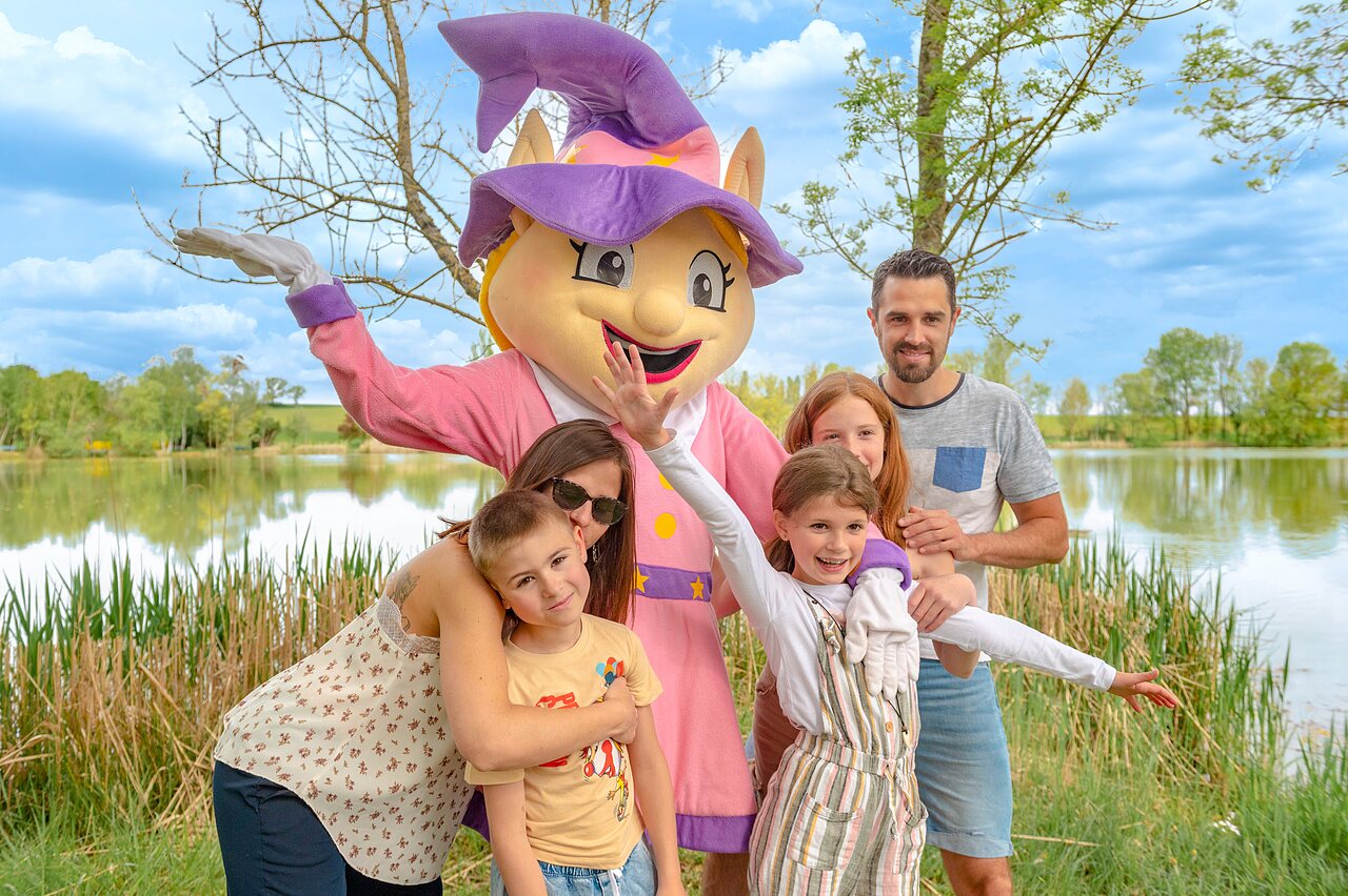 Mascotte en lachende familie bij het meer op camping CAPFUN Mirabelle in VOLSTROFF (57).