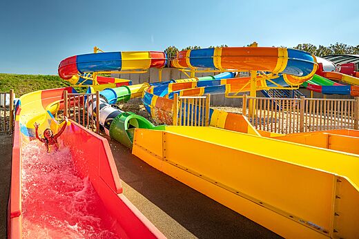 Kleurrijke waterglijbanen met kind plezier makend op camping CAPFUN Mirabelle in VOLSTROFF (57).