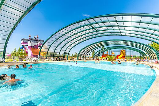 Overdekt zwembad en waterglijbanen met speeltoestellen op camping CAPFUN Mirabelle in VOLSTROFF (57).