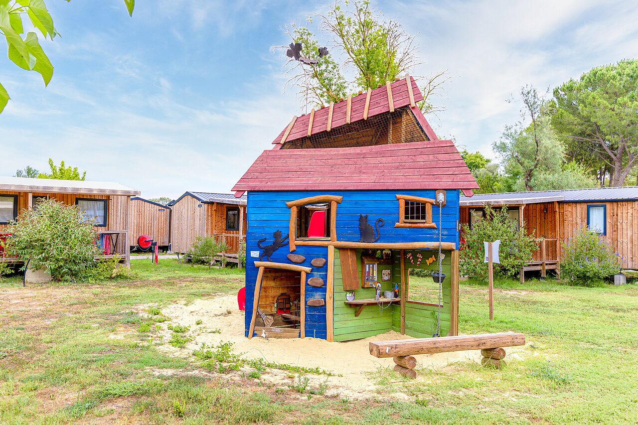 Kleurrijk speelhuisje en stacaravans op camping VAGUES OCEANES Monte Cristo in Vauvert (30).
