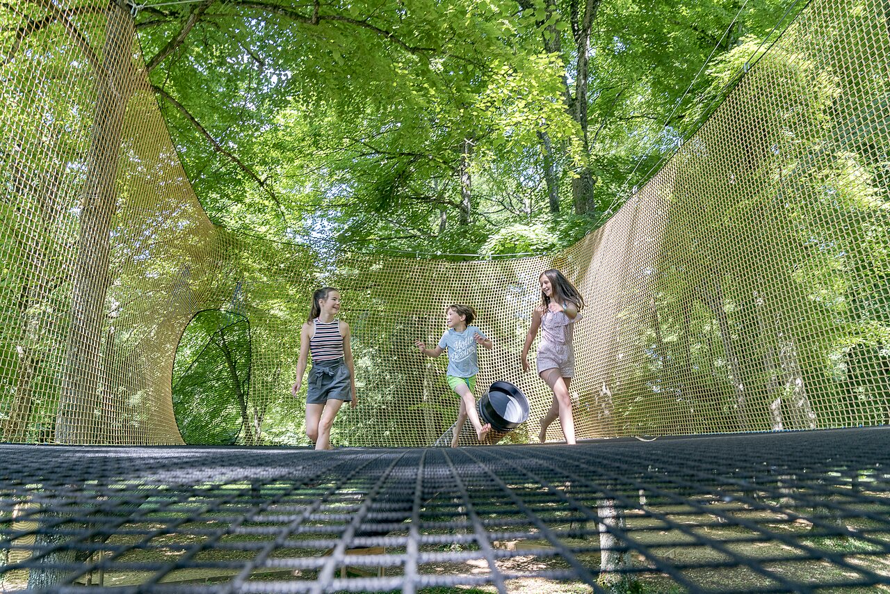 Kinderen spelen op hangende netten tussen bomen, camping CAPFUN Montsabert.