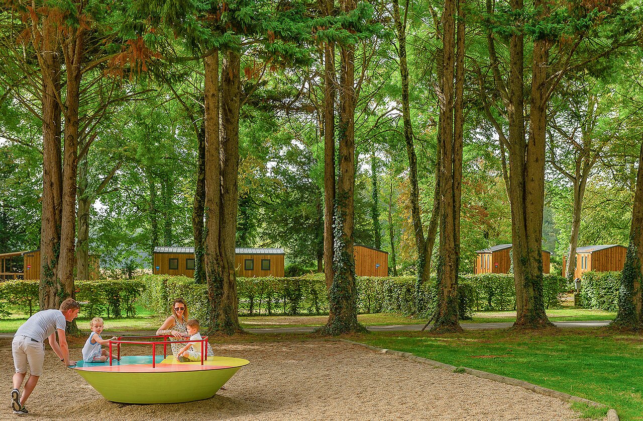 Familie speelt op kleurrijke draaimolen, stacaravans op camping CAPFUN Montsabert in COUTURES (49).