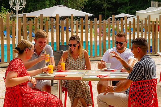 Lachende vrienden drinken een drankje aan de bar van camping CAPFUN Montsabert in COUTURES.