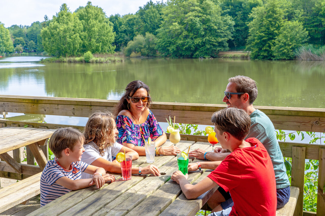 Lachende familie drinkt cocktails aan bar met meerzicht op camping CAPFUN Moulinal in BIRON (24).