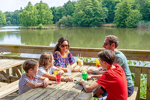 Lachende familie drinkt cocktails op terras aan het meer op camping CAPFUN Moulinal in BIRON (24).