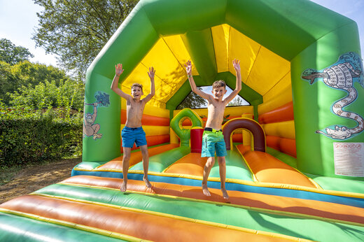 Springkasteel en blije kinderen op camping CLICOCHIC Moulin du Roch.