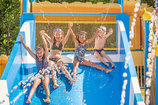 Lachende kinderen op waterglijbaan op camping CLICOCHIC Moulin du Roch in Saint Andre D'Allas.