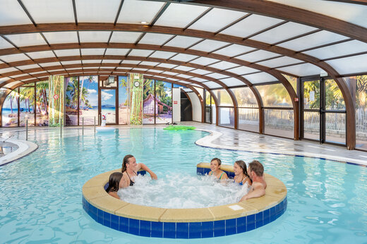 Overdekt zwembad met jacuzzi en familie genietend op camping VAGUES OCEANES Moustoir in Carnac (56).