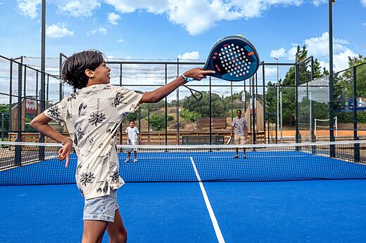Jongen speelt padel op een blauw veld op camping CAPFUN La Nautique in Narbonne (11).
