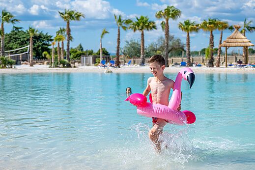 Zwembad, kind met flamingo zwemband op camping CAPFUN La Nautique in Narbonne.