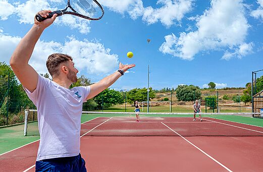 Tennisspeler serveert op een buitenbaan op camping CAPFUN La Nautique in Narbonne (11).