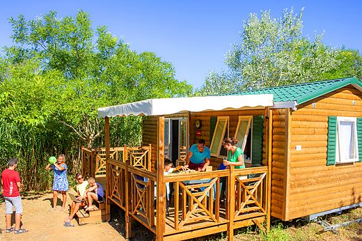 Familie speelt op terras van Mobil-home op camping CAPFUN La Nina in Agde (34).