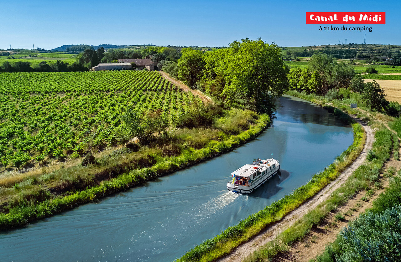 Boot vaart op het Canal du Midi, omringd door wijngaarden en weelderige natuur.